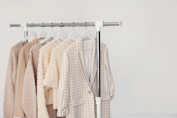 Различные одежды висят на стойке на светлом фоне, крупным планом