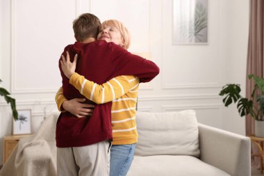 Anne ve oğul birbirlerine sarılıyorlar, mesajlaşmak için yer var.