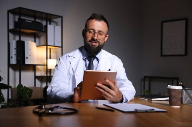 Doktor, gece vardiyası sırasında klinikte tablet üzerinde çalışıyor.