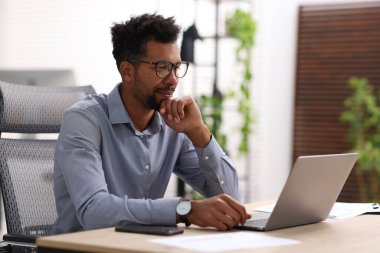 ofiste masada dizüstü bilgisayarda çalışan adam