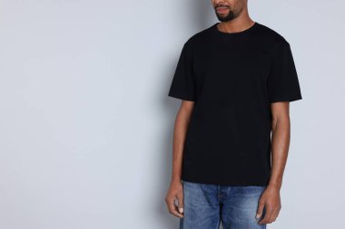 Açık gri arka planda siyah tişört giyen adam, yakın plan. Tasarım için model