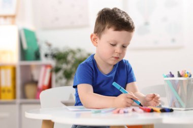 Beyaz masa içinde keçeli kalemle çizim yapan şirin bir çocuk. Metin için boşluk