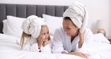Anne ve kız bornoz giyip evde saçlarını havlularla sarıyorlar.