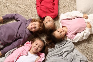 Pijamalı şirin çocuklar evde yerde yatıyor, manzaranın üstünde.