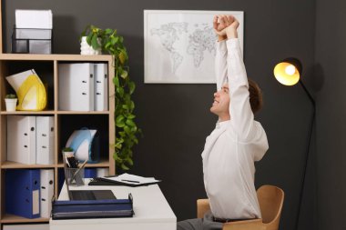 Genç işadamı kollarını uzatıp, masada oturuyor.