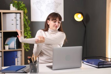 Genç iş kadını ofiste kolunu uzatıyor.