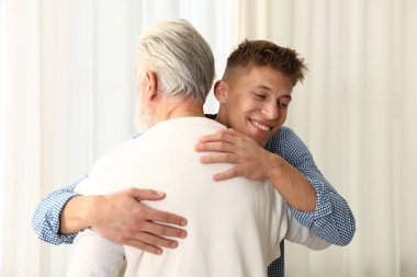 Baba ve oğul evde birbirlerine sarılıyorlar.