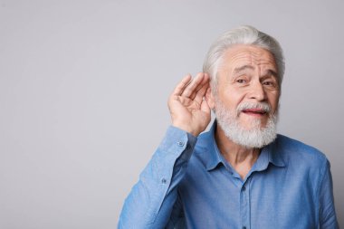 Açık gri arka planda işitme sorunu olan son sınıf öğrencisi. Metin için boşluk