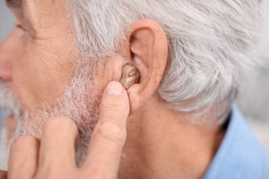 İçeride işitme cihazlı kıdemli adam, yakın plan.