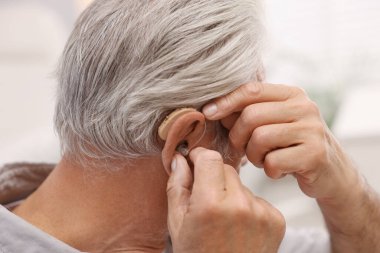 İçeride işitme cihazlı kıdemli adam, yakın plan.