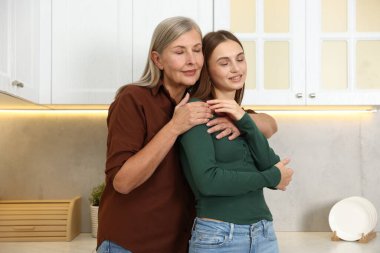 Anne ve kızı mutfakta sarılıyor. Aile bağı