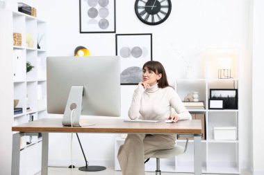 Ofisteki bilgisayarda çalışan genç bir kadın.