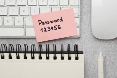 Parola ile kağıt not, bilgisayar klavyesi, fare ve kırtasiye gri tablo üzerinde düz yatıyordu