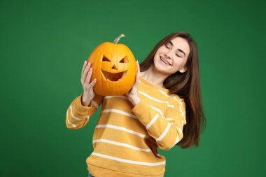 Mutlu Cadılar Bayramı. Yeşil arka planda balkabağı kabağı oyulmuş bir kadın.