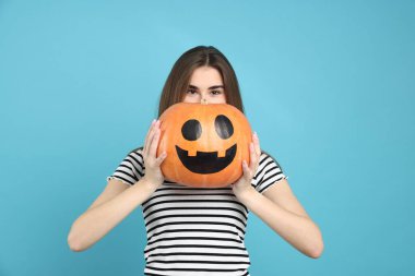 Mutlu Cadılar Bayramı. Açık mavi arka planda balkabağı kabağı olan kadın.