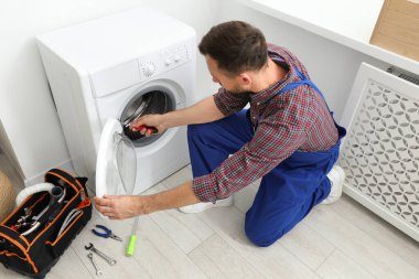 Profesyonel tamirci içeride bozuk çamaşır makinesini tamir ediyor.