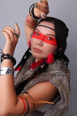 Yüzü açık gri arka planda olan şaman kadın.