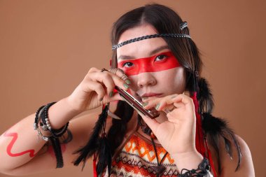 Şaman kadın soluk kahverengi arka planda mızıka çalıyor.