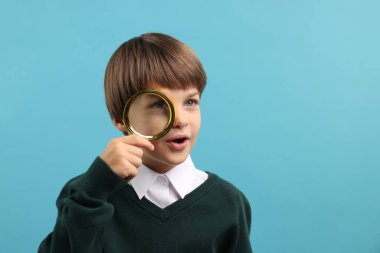 Açık mavi arka planda büyüteç takan küçük bir çocuk. Metin için boşluk