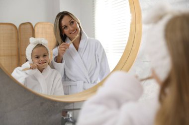 Anne ve kızı banyoda dişlerini fırçalıyorlar.