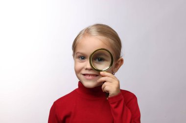 Beyaz arka planda büyüteç olan küçük kız.