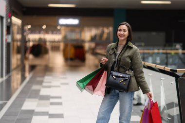 Alışveriş merkezinde farklı alışveriş torbaları olan bir kadın, mesaj için yer.