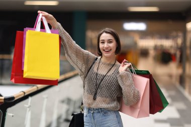 Alışveriş merkezinde farklı çantaları olan bir kadın.