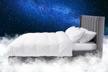 Yıldızlı gece gökyüzünde kabarık bulutların üzerinde büyük bir yatak.