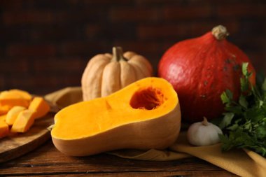 Taze balkabakları ve baharatlar ahşap masada tuğla duvara karşı, yakın plan.