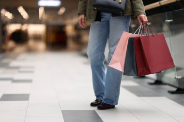 Alışveriş merkezinde farklı alışveriş torbaları olan bir kadın, yakın plan. Metin için boşluk