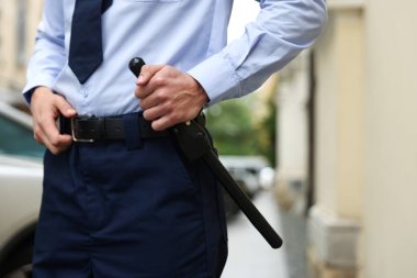 Şehir sokağında coplu bir polis memuru, yakın plan.