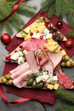 Lezzetli Noel Şarküteri tahtası. Atıştırmalıkları, köknar dalları ve gri desenli masalarda takılar.