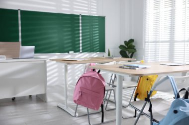 Sınıfta yeşil karatahta, sıralar ve sandalyeler.