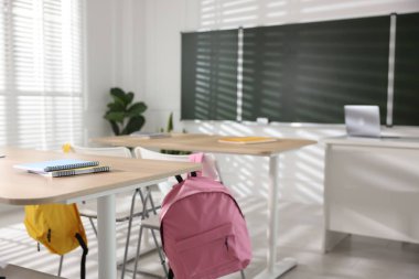 Sınıfta yeşil karatahta, sıralar ve sandalyeler.