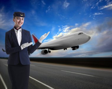 Üniformalı gülümseyen hostes uçağı işaret ediyor.