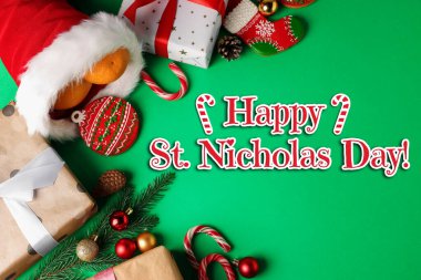 Kırmızı çizmeli, hediye kutulı ve yeşil arka planda şenlikli Aziz Niklas Günü tebrik kartı tasarımınız kutlu olsun.