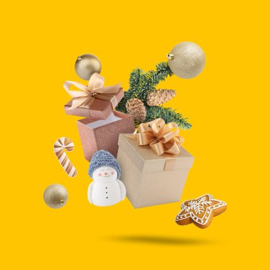 Noel ya da yeni yıl kutlaması. Hediye kutuları, kurabiyeler ve turuncu arka planda uçuşan şenlik dekorları.