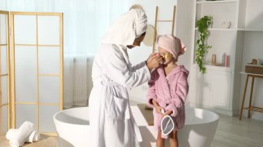 Anne ve kız göz bantlı ve banyoda bornoz giyen saçları sarılı.