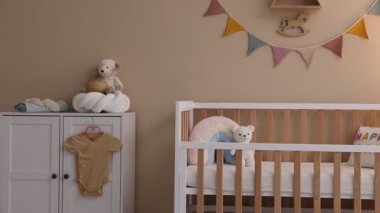 Bebek odası, beşik, masa, dekor ve şifonyer. Kamera sağa hareket ediyor