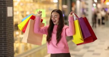 Alışveriş merkezinde farklı çantaları olan bir kadın.