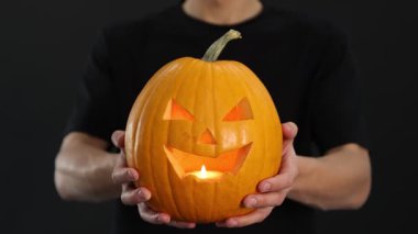 Cadılar Bayramı kutlaması. Siyah arka planda balkabağı olan adam, yakın plan.