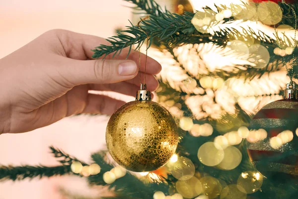 Noel tebrik kartı tasarımı. Bir kadın köknar ağacını şenlikli baloyla süslüyor. Bokeh ışıkları