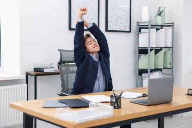 Genç işadamı kollarını uzatıp, masada oturuyor.