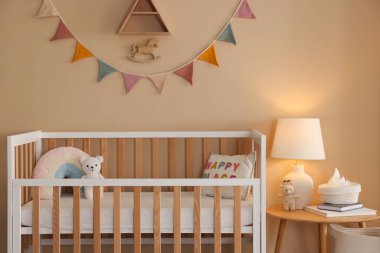 Beşik, masa, lamba ve dekorlu şık bir bebek odası. İç tasarım