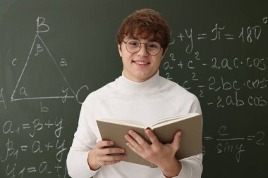 Okula dönelim. Matematik ödevi olan bir öğrenci karatahtanın yanında kitap tutuyor.