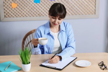 Kahve molası. Güzel bir kadın, bardakla kapalı bir masada yazıyor.