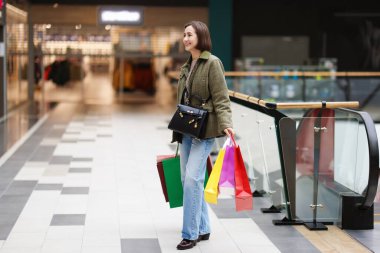 Alışveriş merkezinde farklı alışveriş torbaları olan bir kadın, mesaj için yer.