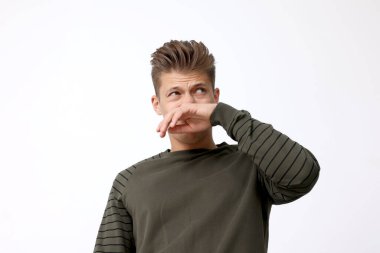 Genç adam kötü kokudan muzdarip ve burnunu kapalı bir yere kapatmış.