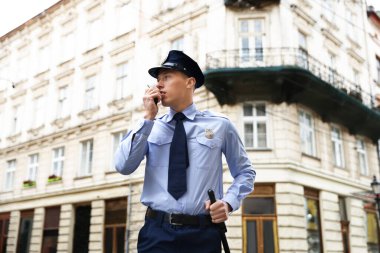 Polis memuru radyoda konuşuyor, şehir caddesinde, düşük açılı.