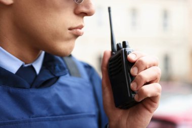 Şehir caddesinde telsizi olan bir polis memuru, yakın plan.